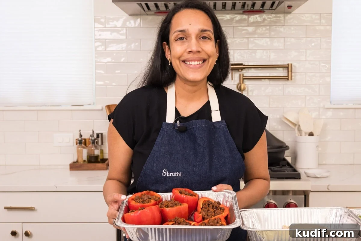 Smoky Black Bean Stuffed Peppers with Cilantro Lime Rice 5 Shruthi holding tray of black bean stuffed peppers ready to be baked.