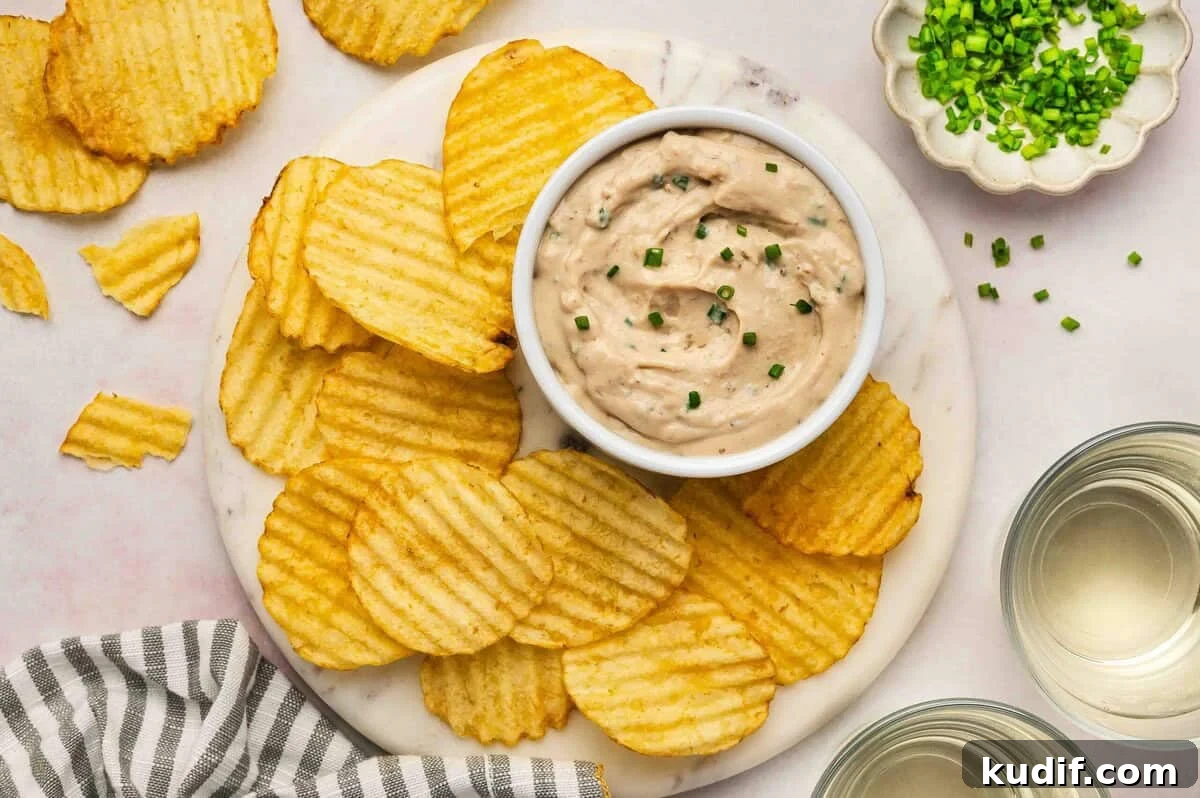 Creamy French Onion Dip Recipe for Parties and Snacks 8 Overhead view of French onion dip garnished with chives, surrounded by crinkle-cut potato chips