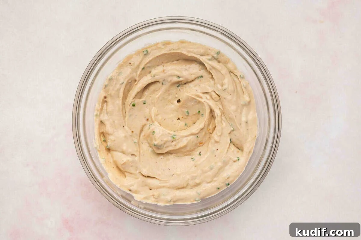 Creamy French Onion Dip Recipe for Parties and Snacks 6 Creamy French onion dip fully mixed in a glass bowl, showing smooth texture with flecks of onion and chives
