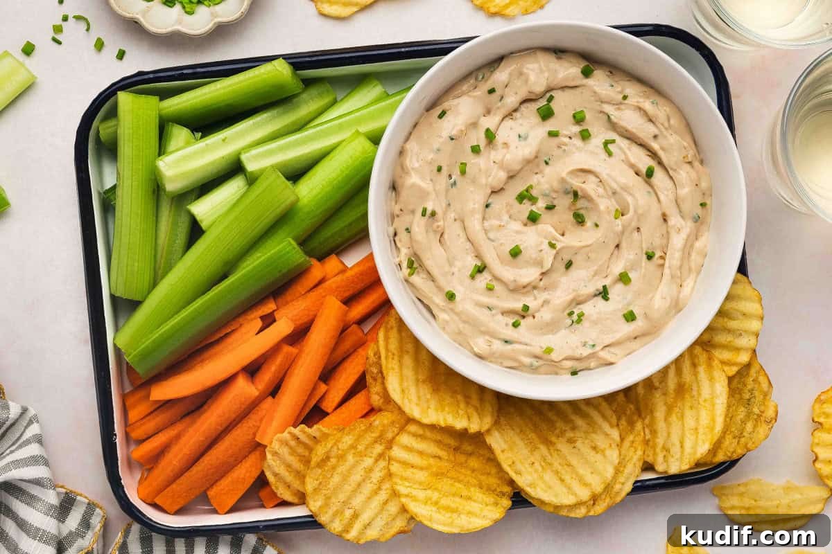 Creamy French Onion Dip Recipe for Parties and Snacks 7 French onion dip served on a snack tray with crinkle-cut potato chips, carrot sticks, and celery