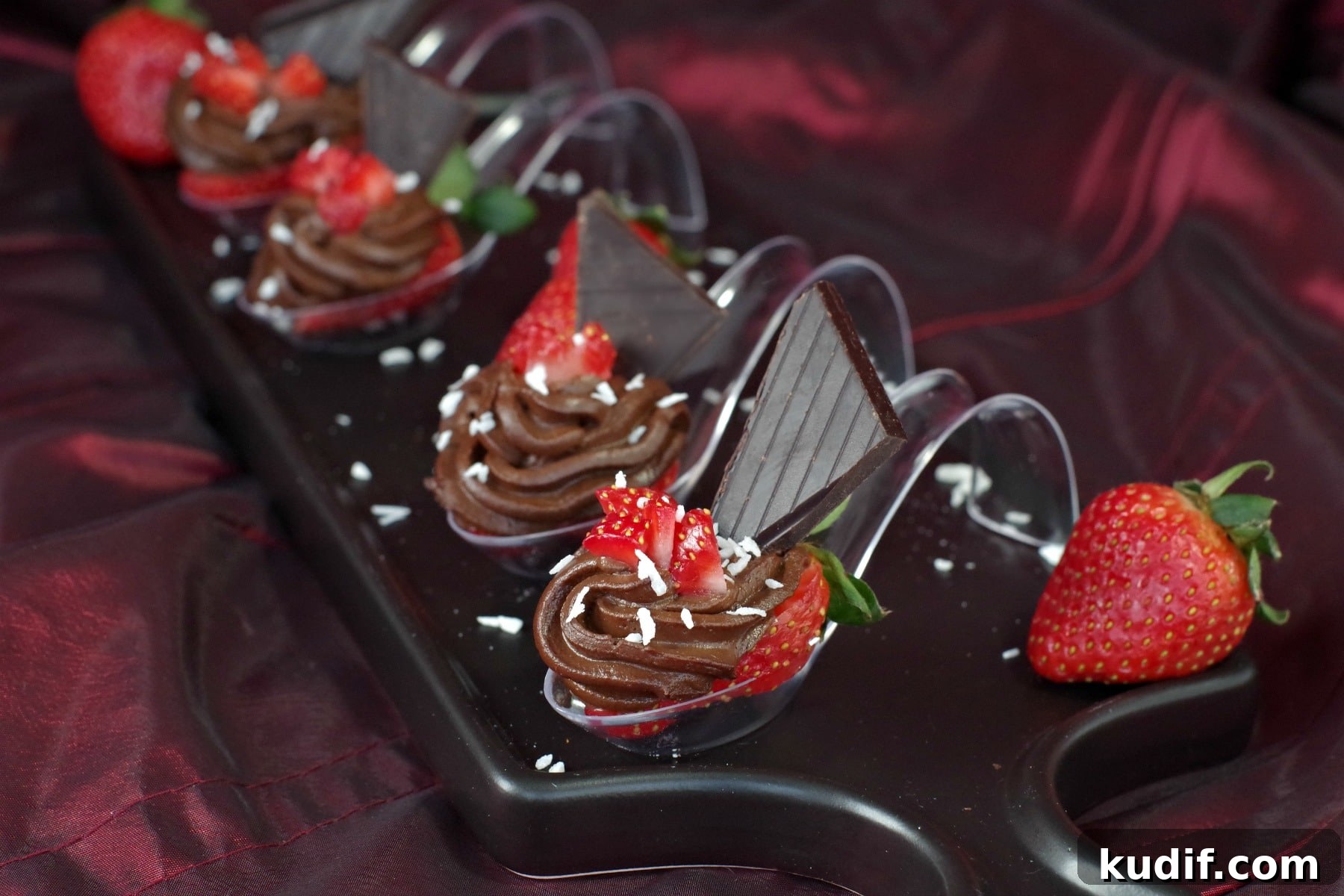4 Chocolate Avocado strawberry desserts on spoons on a black appetizer tray