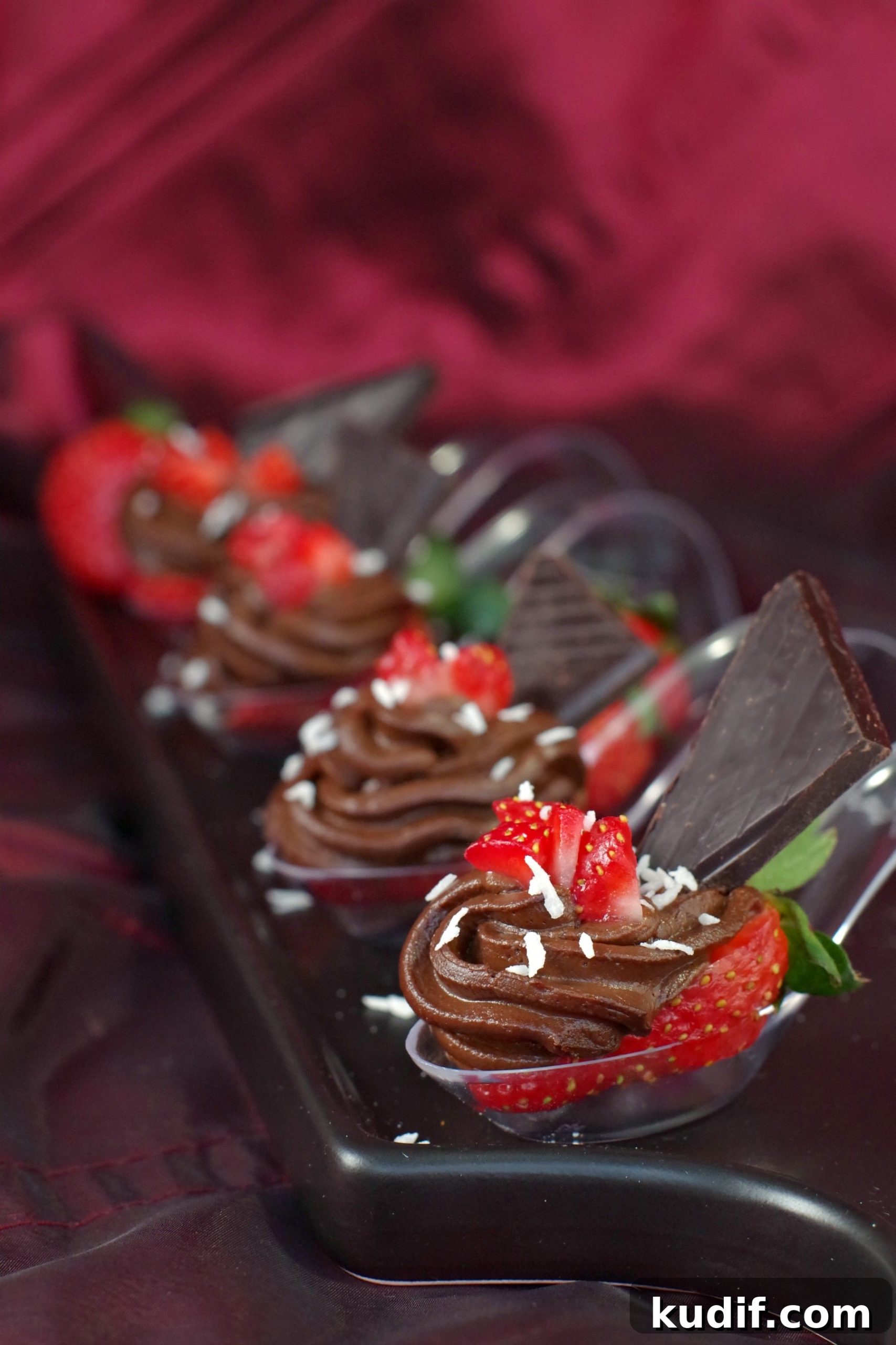 4 Chocolate Avocado strawberry desserts on spoons on a black appetizer tray