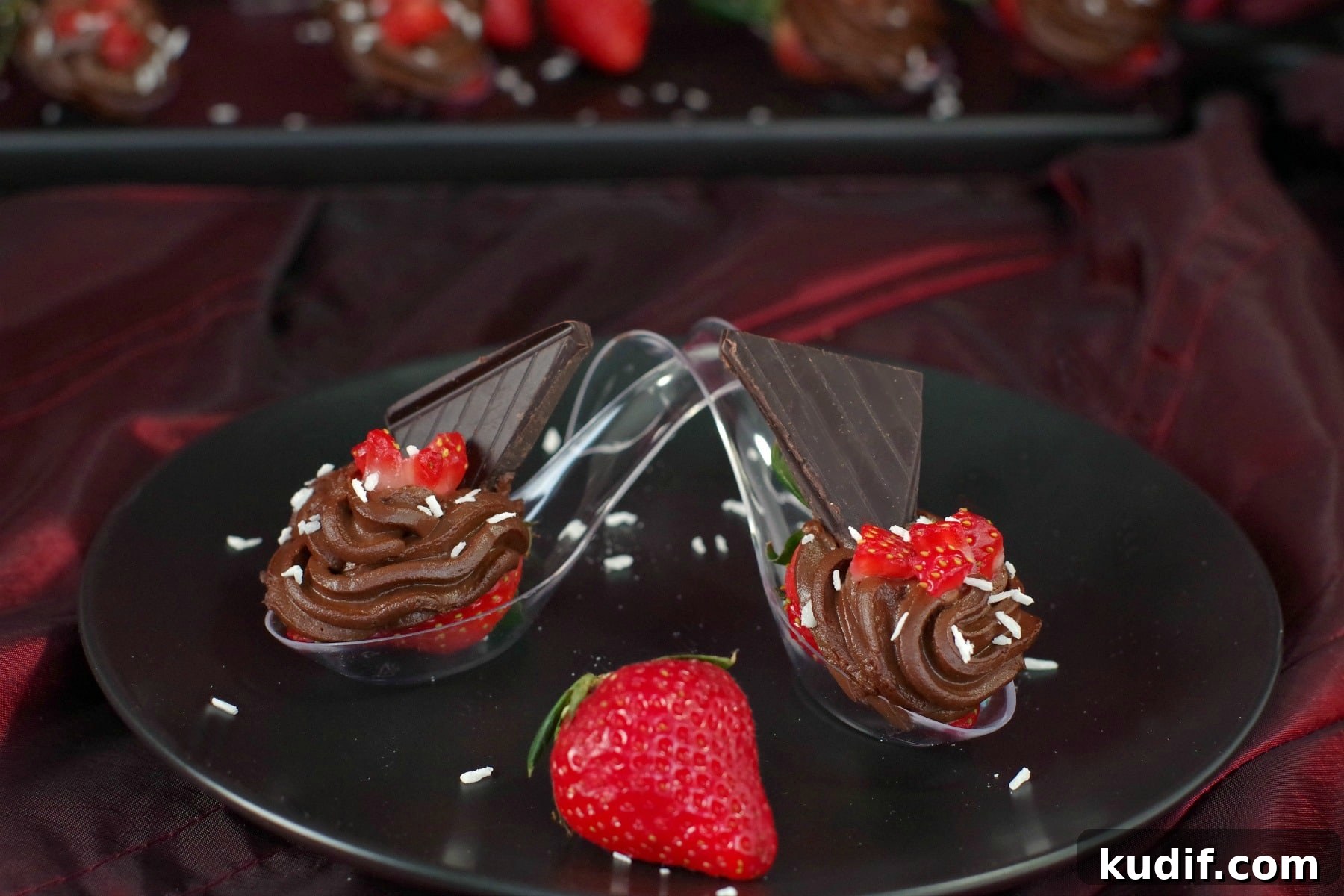 2 Healthy Valentine's Day Desserts on spoons crossed over each other with a whole strawberry in the middle