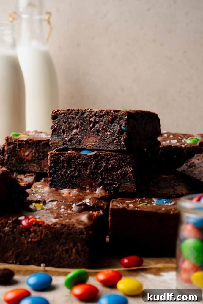 A stack of two fudgy m&m brownies with milk bottles in the background.