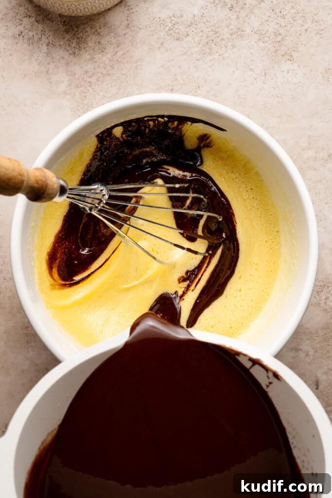 The chocolate mixture being whisked into the egg mixture.