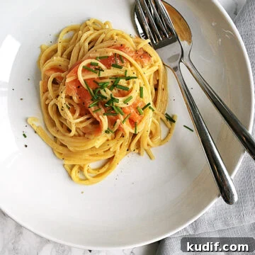 a plate with creamy smoked salmon spaghetti carbonara beside a napkin and cutlery