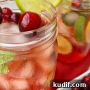 cranberry mojito with mint flavoring served in a cup, and garnished with cranberries