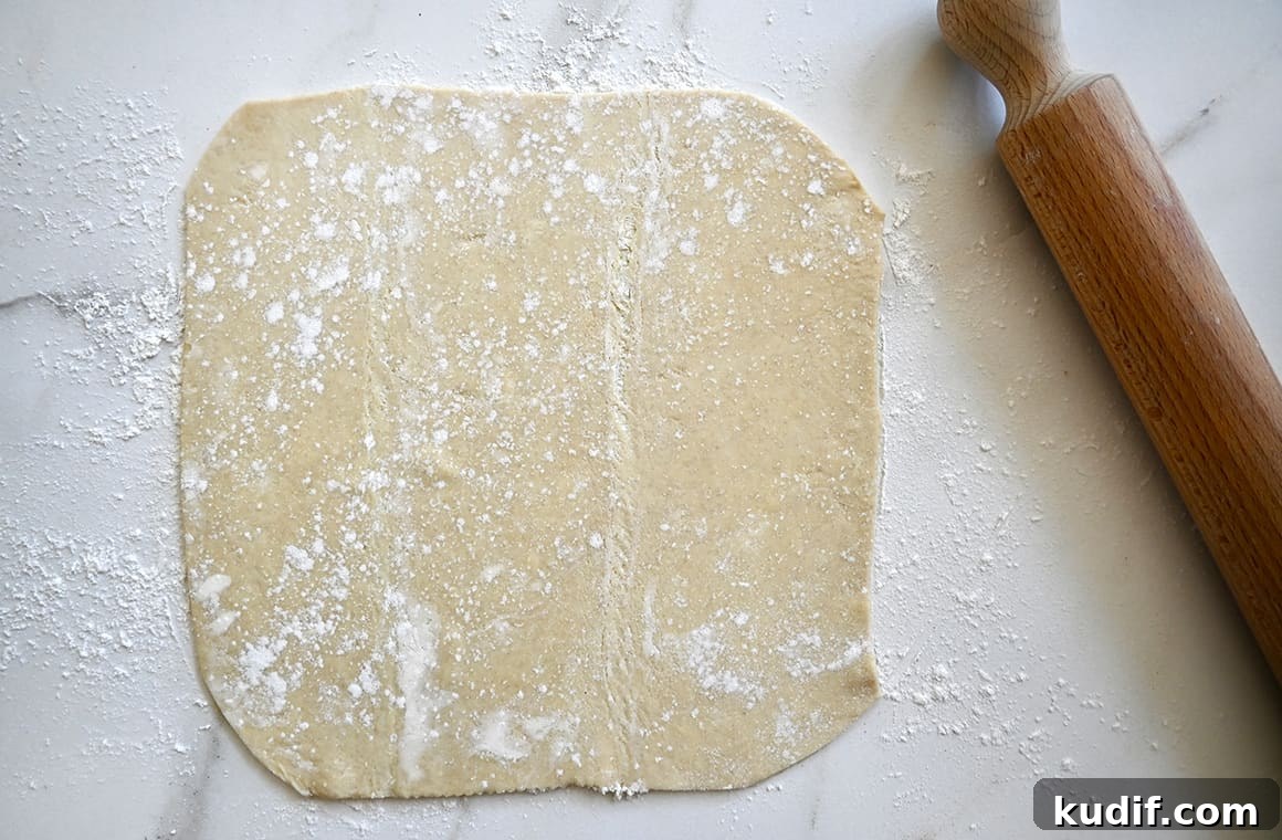 Puff Pastry Galette Recipe: Step-by-Step Fruit and Savory Ideas 3 A top-down view of a puff pastry sheet on a lightly floured surface next to a rolling pin