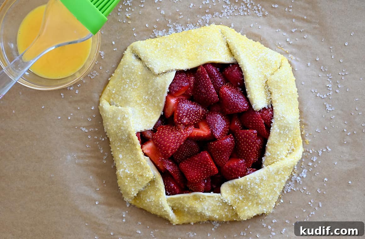 Puff Pastry Galette Recipe: Step-by-Step Fruit and Savory Ideas 5 A small bowl containing egg wash next to an unbaked galette sprinkled with sanding sugar