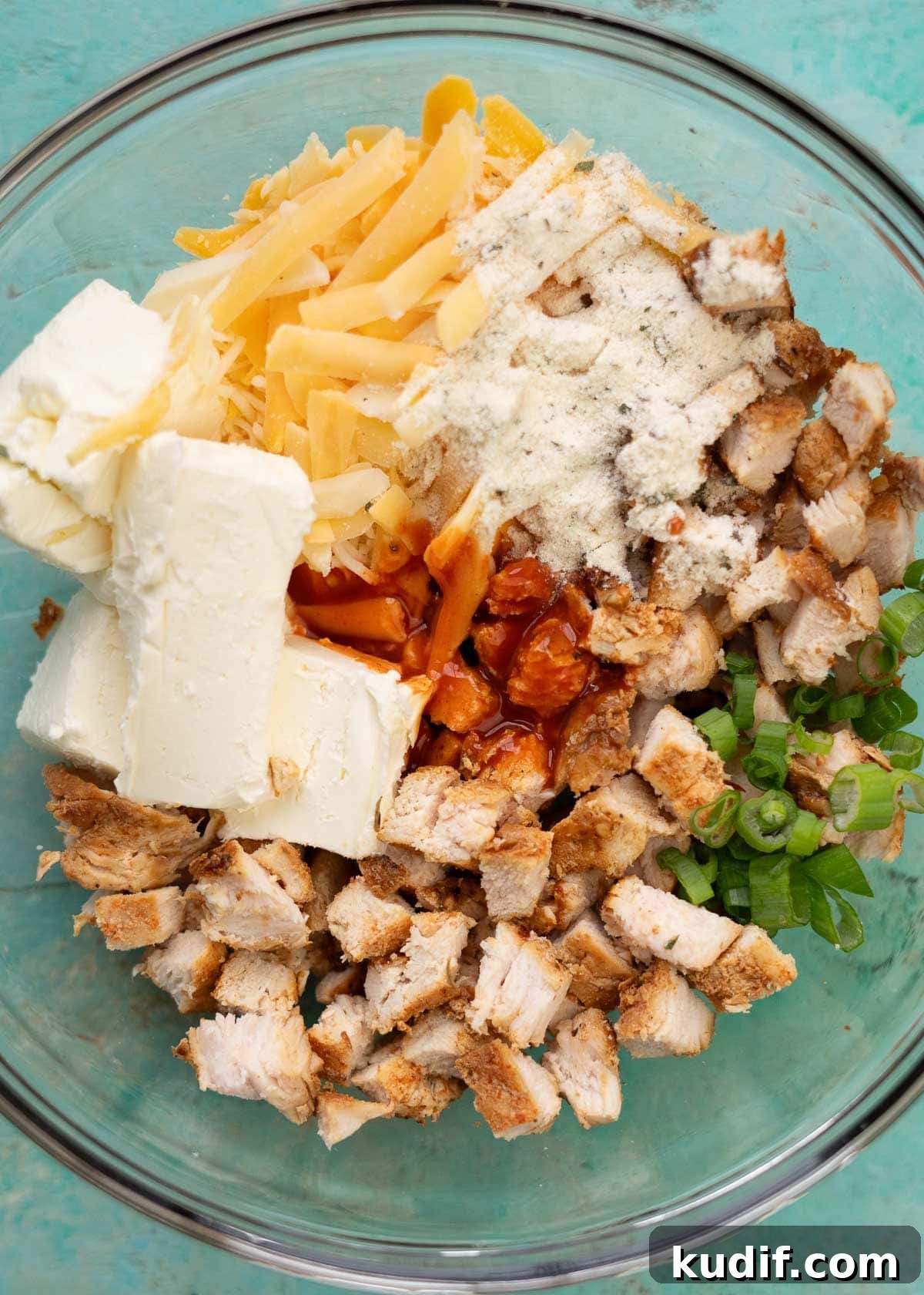 Spicy Buffalo Chicken Taquitos Recipe for Game Day Snacks 4 chicken, cream cheese, shredded cheese, buffalo sauce, and ranch seasoning in a glass bowl