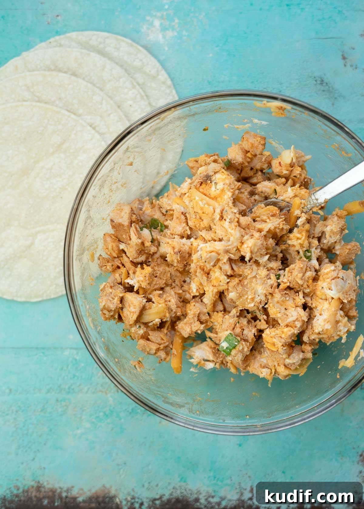 Spicy Buffalo Chicken Taquitos Recipe for Game Day Snacks 5 Cheesy buffalo chicken mixture in a glass bowl beside corn tortillas