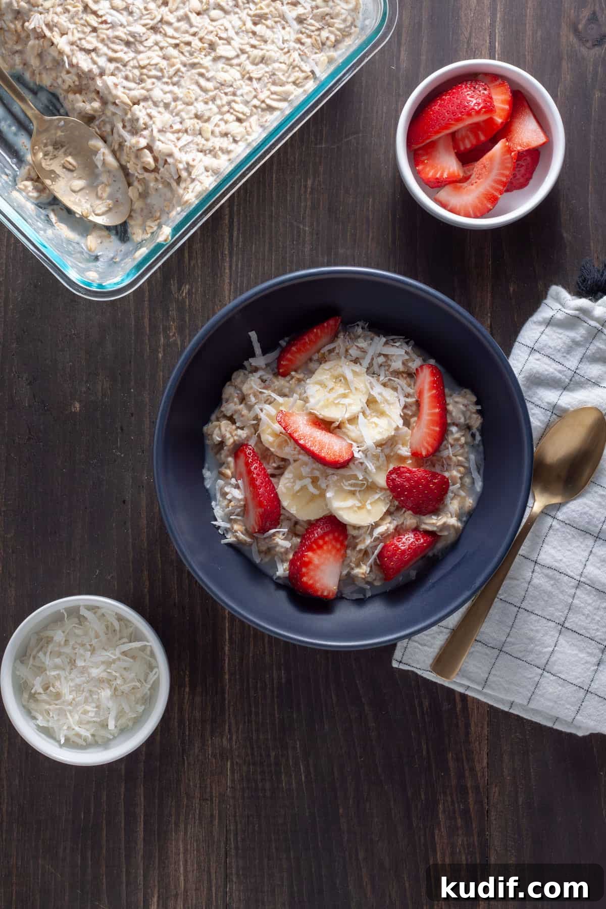 A bowl of overnight oats with coconut milk topped with shredded coconut, berries and maple syrup.
