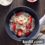A bowl of overnight oats with coconut milk topped with shredded coconut, berries and maple syrup.