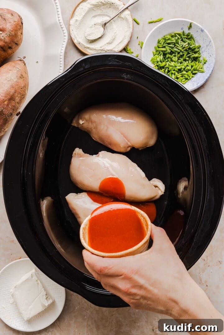 Buffalo Chicken Stuffed Sweet Potatoes Recipe for Spicy Weeknight Meals 4 Raw chicken breast and buffalo sauce in slow cooker for buffalo chicken sweet potatoes.