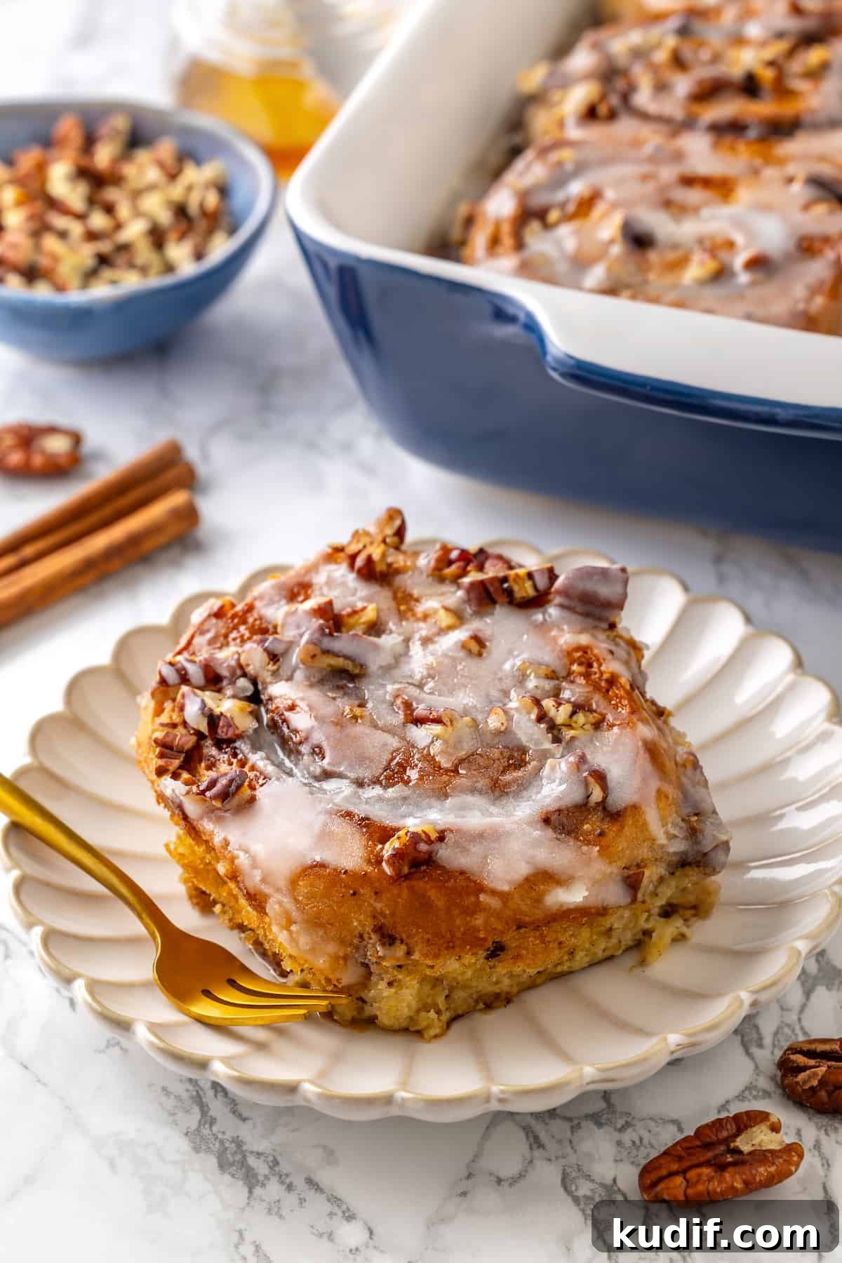 This vegan cinnamon roll French toast recipe has soft homemade cinnamon rolls baked in custard. The best cozy breakfast or holiday brunch! Cinnamon roll French toast on white plate with pan of French toast in background