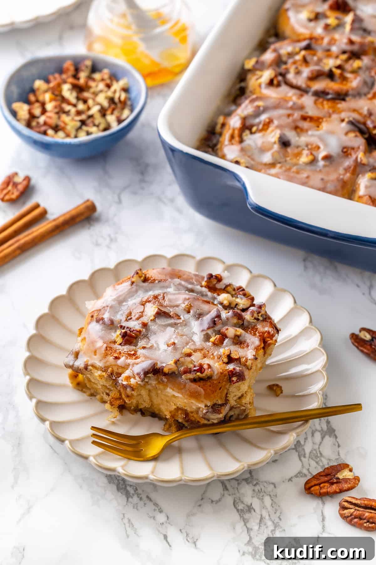 This vegan cinnamon roll French toast recipe has soft homemade cinnamon rolls baked in custard. The best cozy breakfast or holiday brunch! Portion of cinnamon roll French toast on white plate with remaining French toast in baking dish in background