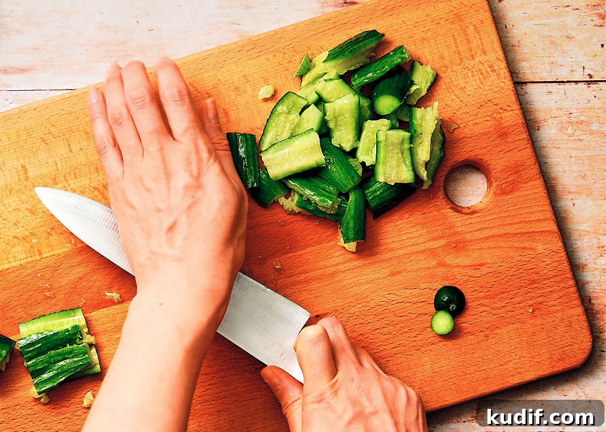 Spicy Cucumber Salad Recipe: Quick Tangy Side Dish 6 Smashing cucumbers on a cutting board with a knife.