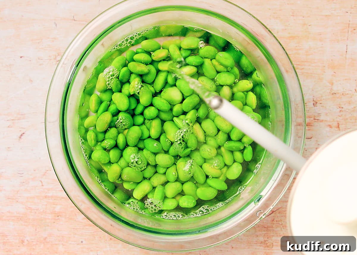 Spicy Cucumber Salad Recipe: Quick Tangy Side Dish 10 Pouring boiling water over frozen edamame beans to defrost them.