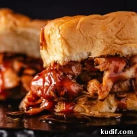 A closeup shot of a shredded chicken sandwich dripping with BBQ sauce.