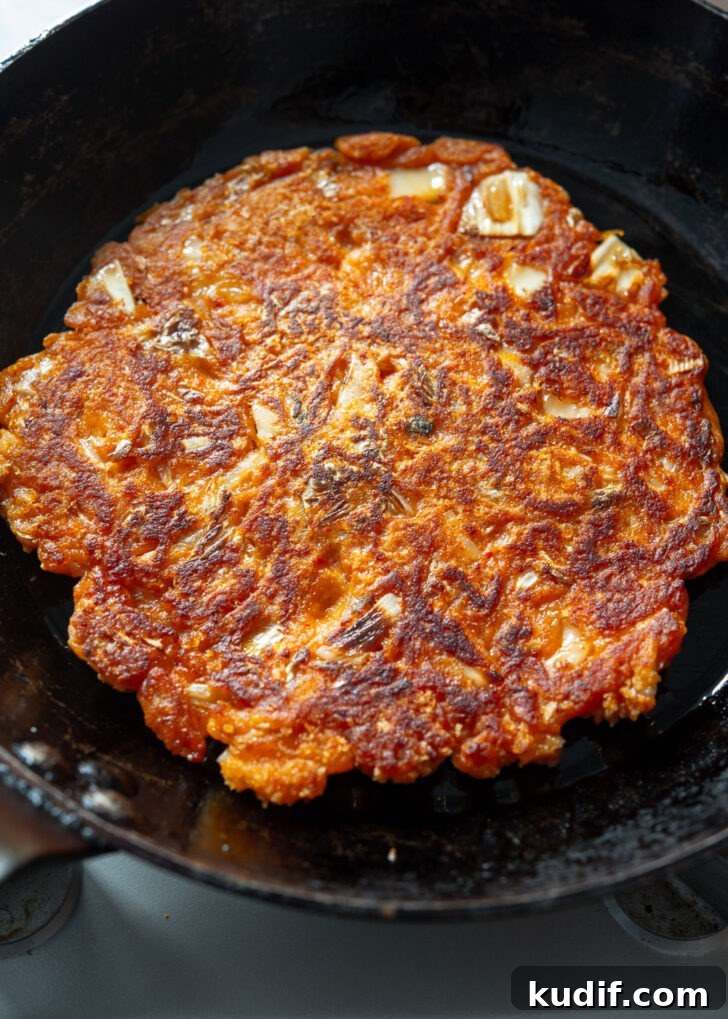 Crispy Kimchi Pancakes (Kimchi Jeon) Recipe for Perfect Pan-Fried Kimchi Cakes 11 Crispy kimchi pancake (kimchi jeon) frying in a pan until golden brown.