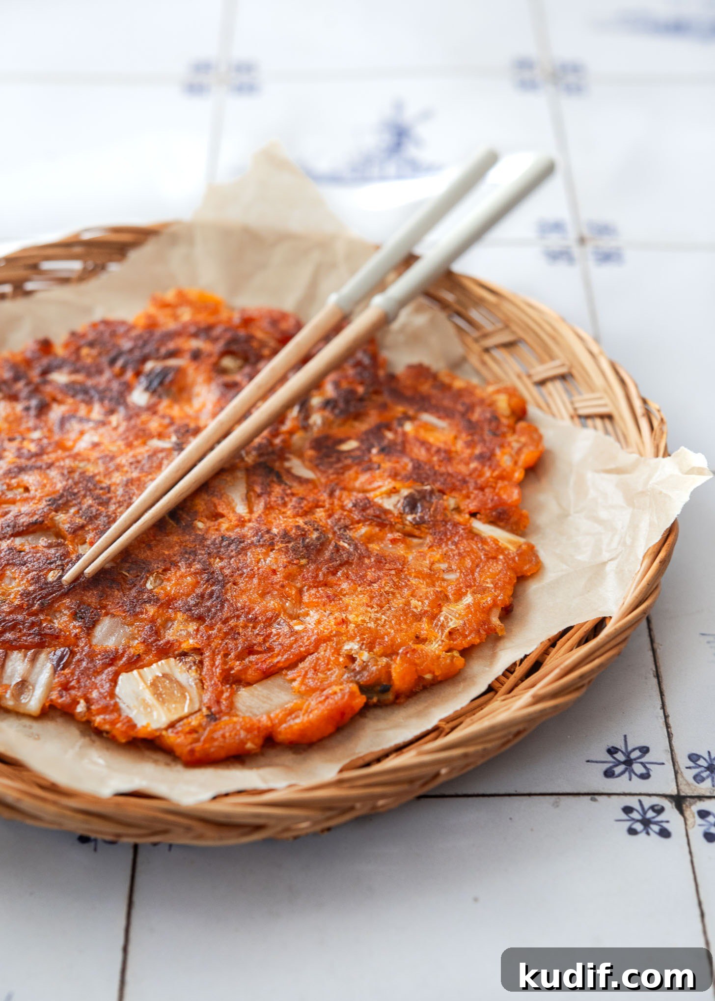 Crispy Kimchi Pancakes (Kimchi Jeon) Recipe for Perfect Pan-Fried Kimchi Cakes 13 Crispy kimchi pancake with chopsticks on a serving dish.