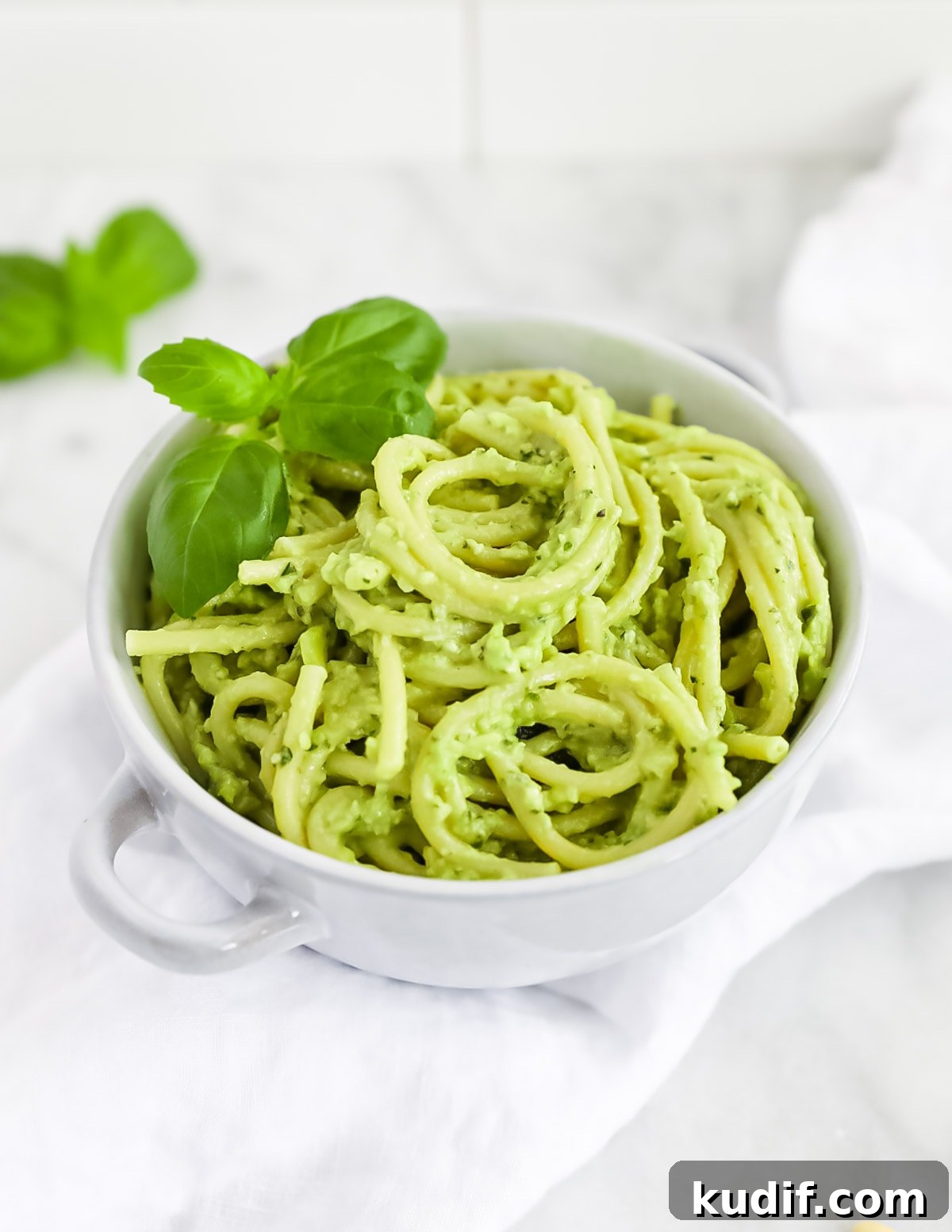 Creamy Pesto Sauce Recipe: Rich Basil Sauce for Pasta & More 2 Creamy avocado pesto over thick spaghetti noodles, garnished with fresh basil leaves.