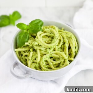 Creamy Pesto Sauce Recipe: Rich Basil Sauce for Pasta & More 11 A blue bowl filled with spaghetti noodles covered in a green pesto, garnished with fresh basil