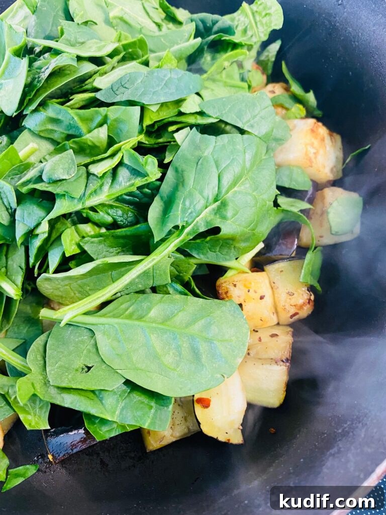 Mediterranean Quinoa Bowls with Fresh Veggies & Lemon Tahini 5 adding spinach to the cooked eggplant