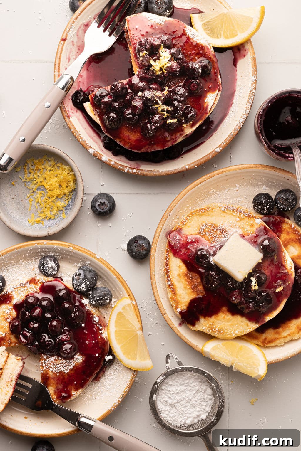 Lemon Pancakes with Blueberry Maple Syrup Recipe 13 Three plates of pancakes with different levels of toppings—one with a butter pat melting over the blueberry compote.