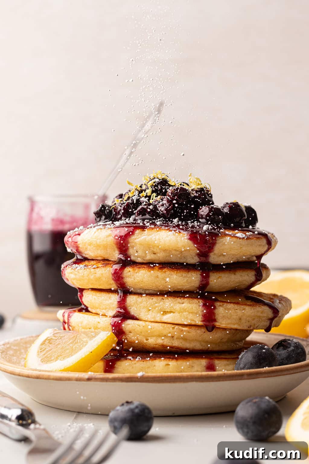 Lemon Pancakes with Blueberry Maple Syrup Recipe 14 A stack of fluffy pancakes topped with blueberry compote, lemon zest, and blueberry syrup.