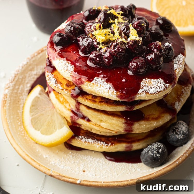 Lemon Pancakes with Blueberry Maple Syrup Recipe 15 A top-down view of a pancake stack covered in blueberry compote, powdered sugar, and lemon zest.