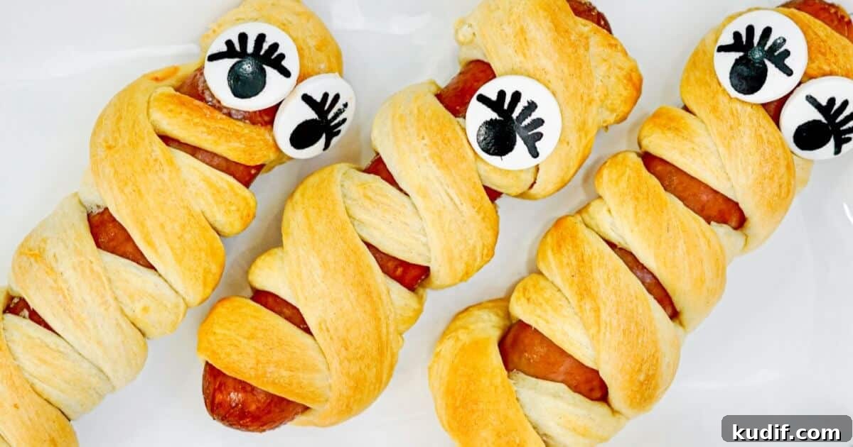15 Spooky Halloween BBQ Recipes for Party-Worthy Grilling 6 a sausage wrapped with pastry and some eyeballs to look like a mummy