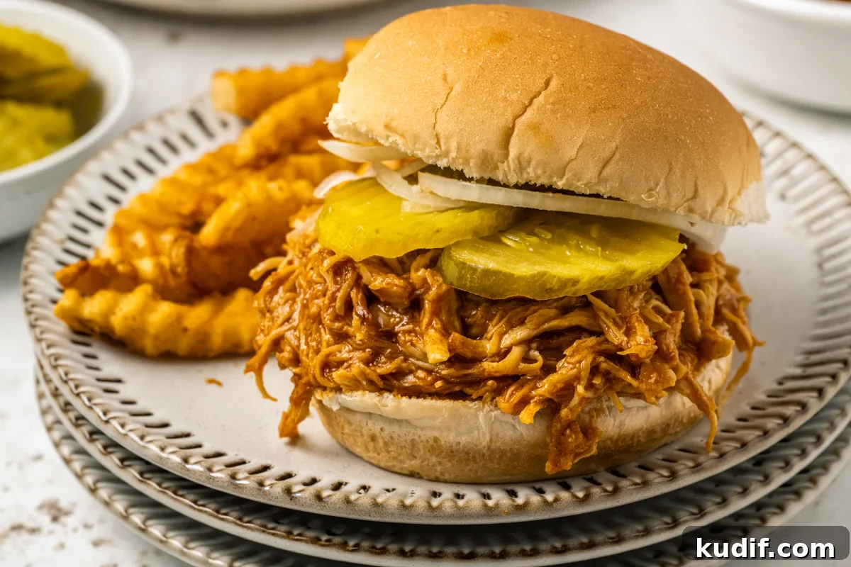 Spicy chicken sandwich on a plate wit fries.