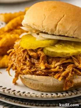 Spicy chicken sandwich on a plate wit fries.