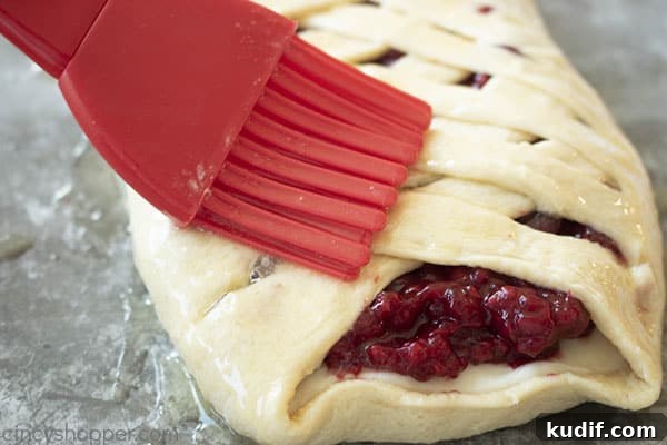 Raspberry Crescent Danish: Flaky Pastry Recipe for Brunch 14 brushing melted butter onto braided pastry dough