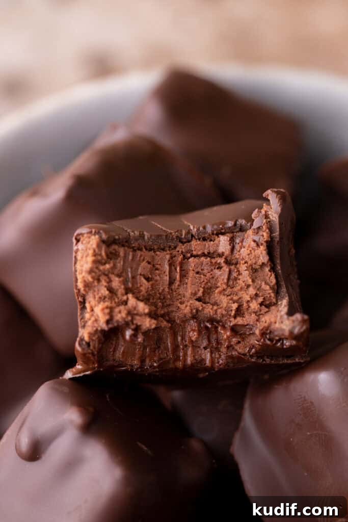 A partially eaten chocolate candy revealing its soft chocolate mousse interior.