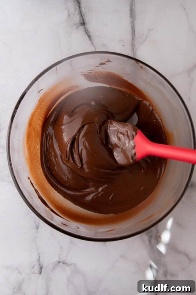 Melted dark chocolate in a mixing bowl ready for dipping homemade candy.