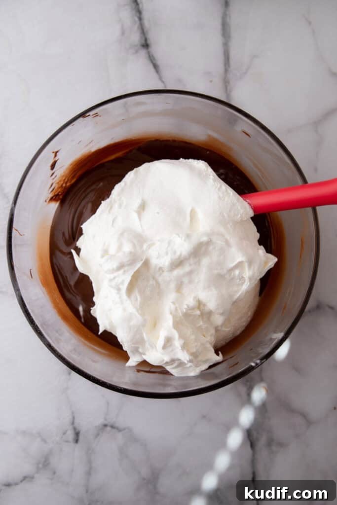 Cool Whip added to a bowl of melted chocolate to create the fluffy candy mixture.