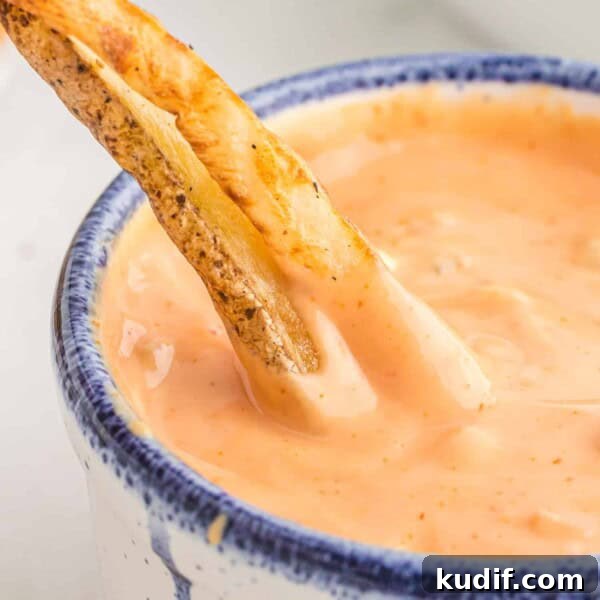 Fries being dipped into fry sauce.