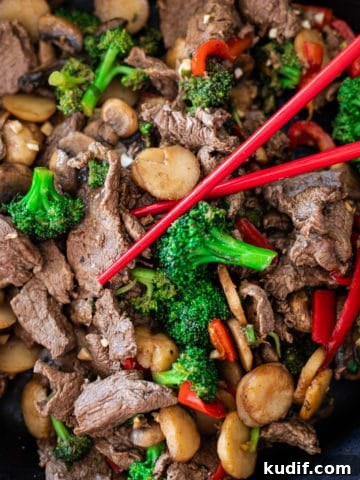 A closeup of beef stir fry with chop sticks.