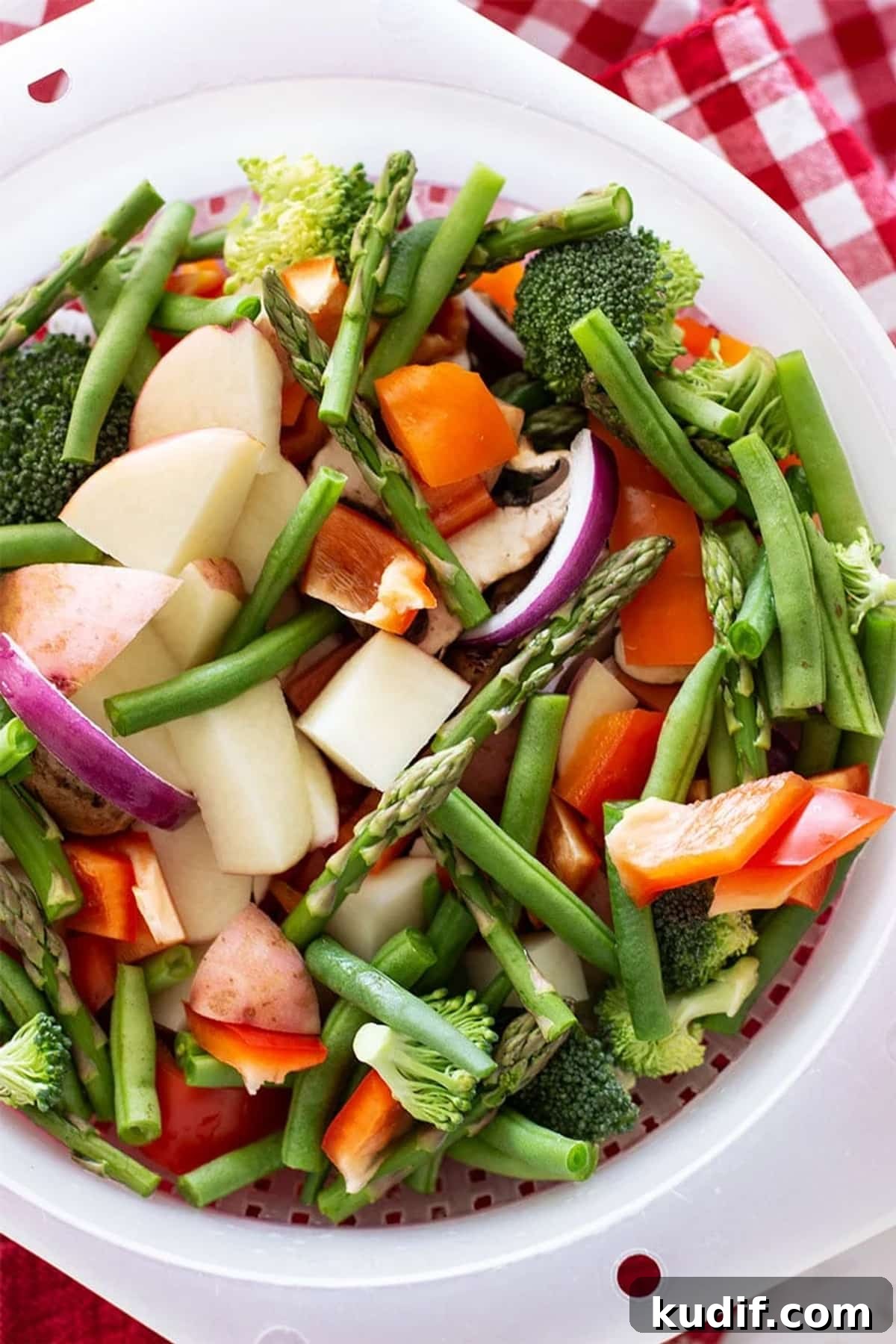 Sheet Pan Sausage with Roasted Vegetables Recipe 5 Colander of fresh chopped vegetables containing asparagus, peppers, onions, broccoli and green beans.