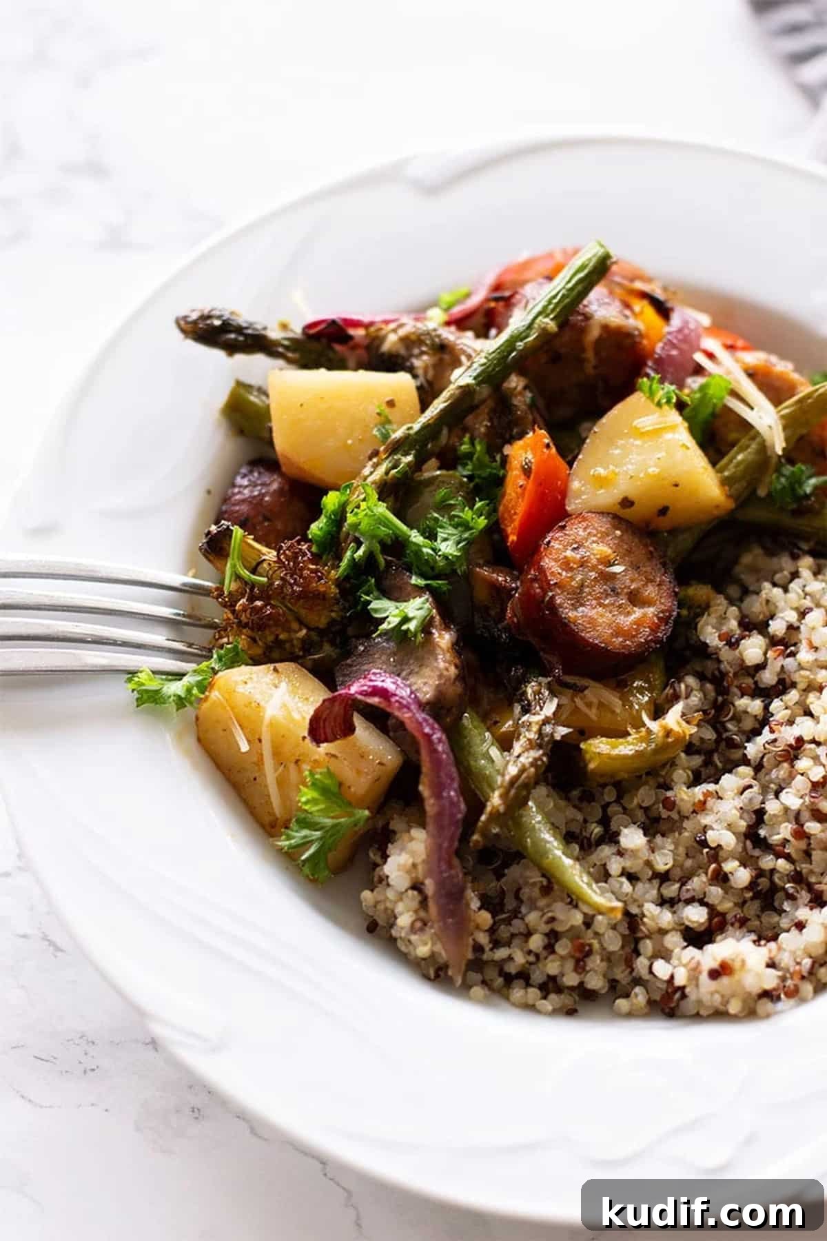 Sheet Pan Sausage with Roasted Vegetables Recipe 10 White bowl containing One Pan Smoked Sausage and Vegetables served with quinoa.