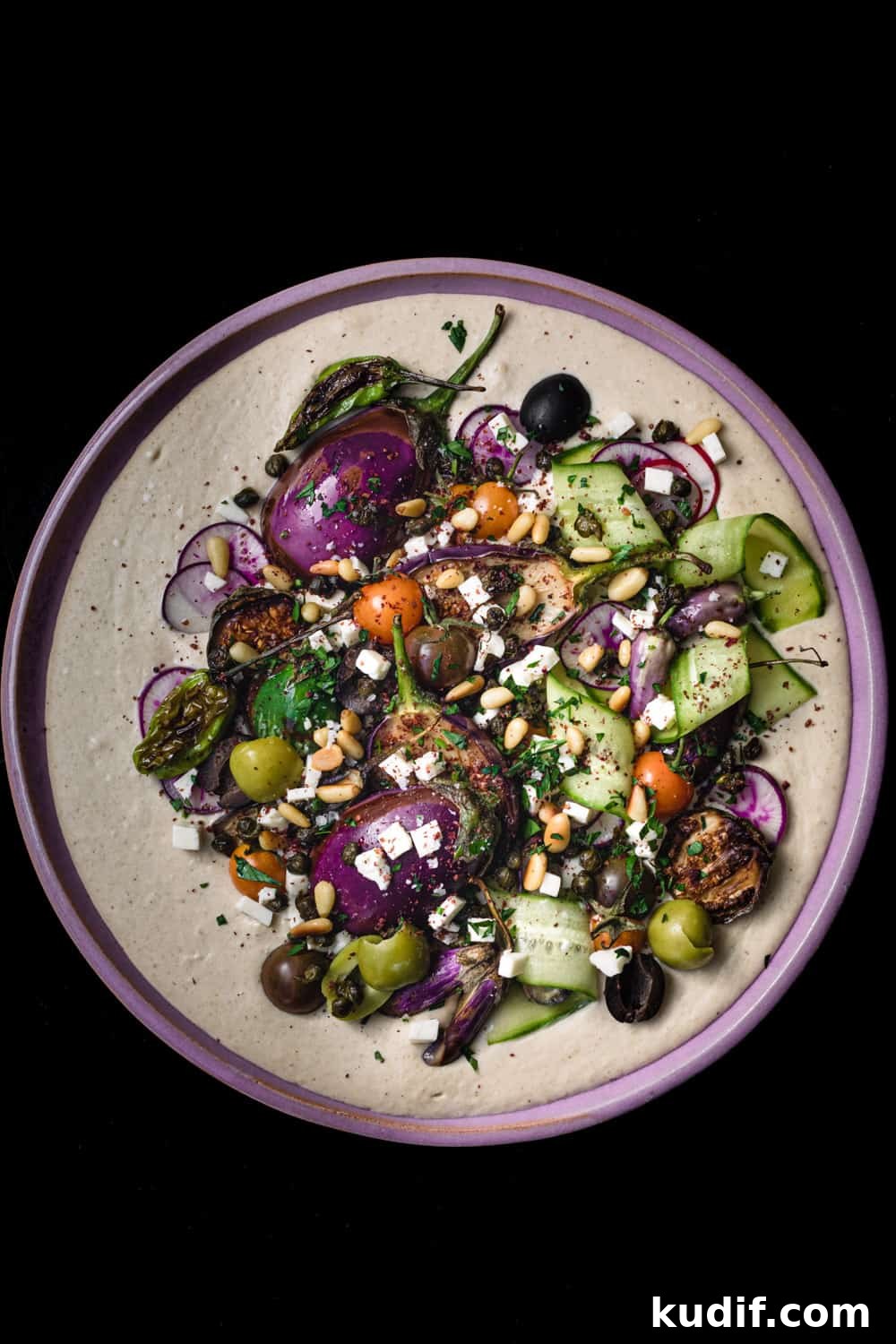 Loaded Hummus: Mediterranean 7-Layer Dip with Veggies & Feta 5 hummus is on a pink plate, with seasonal fruits and veggies, overhead on a black background.