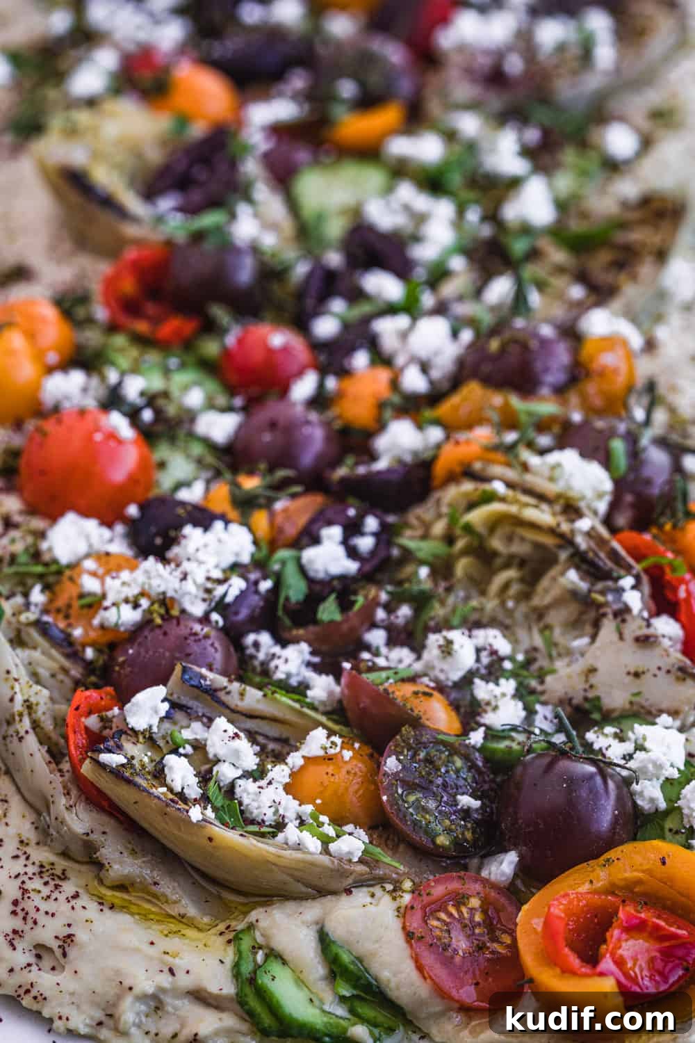Loaded Hummus: Mediterranean 7-Layer Dip with Veggies & Feta 6 loaded 7 layer hummus with artichoke hearts, tomatoes, cucumbers and more; side angle and close up