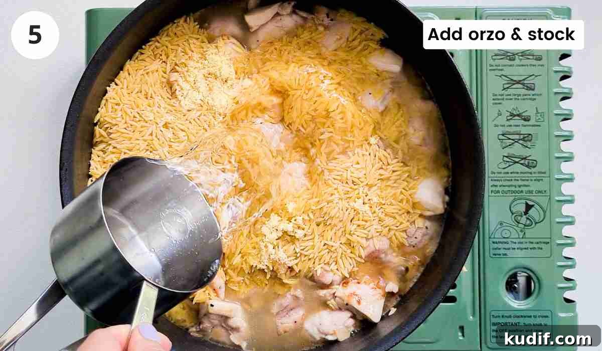 Creamy Chicken and Orzo Skillet Recipe 8 water being poured in a pan filled with uncooked orzo and chicken cubes