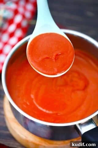 a spoonful of enchilada sauce over a saucepan with the sauce