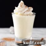 Vanilla pudding shots topped with whipped cream, on a black background.