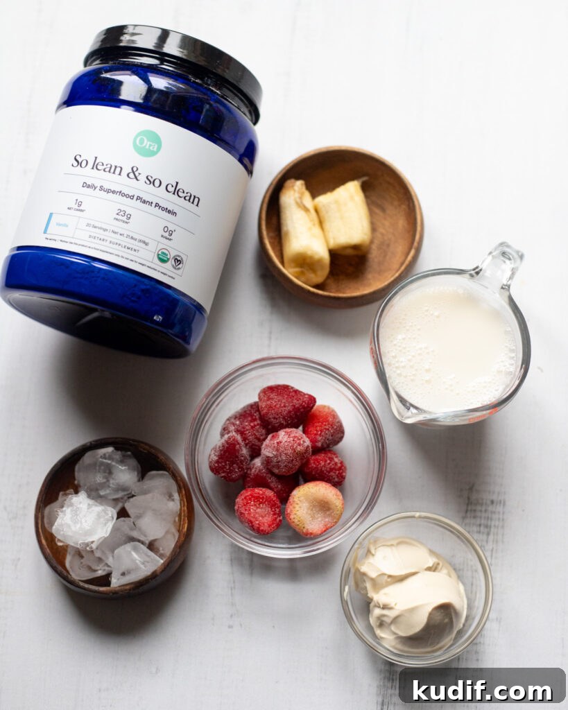 Vegan Strawberries and Cream Protein Breakfast Smoothie 3 overhead view of ingredients for strawberries & cream smoothie, orange protein, banana, frozen strawberry, plant milk, ice and vegan greek yogurt